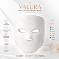 A white Valura 7-color LED facial mask centered on a soft white background with product text, icons, and a color legend. The Valura brand name is prominently displayed at the top, and the mask features cutouts for the eyes, nose, and mouth.