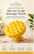 A yellow silicone scalp massager brush by Valura, shown on a beige spa-themed background with a rolled towel and green leaves. The image includes product text, benefits icons, and the Valura brand logo.